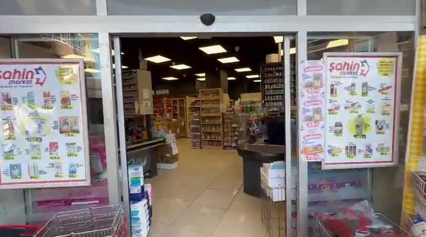 Giriş kapısının camında asılı Şahin Market haftalık kampanya afişleri
